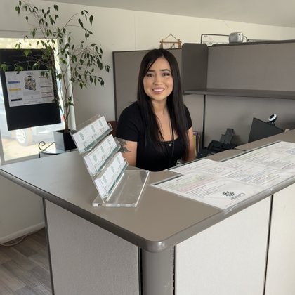 Akela Scott smiling from behind the front desk at the Trinity office