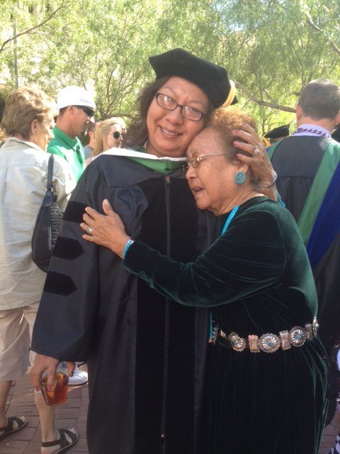 Dr. SueAnn Manuelito in her doctoral graduation regalia, embracing her mother